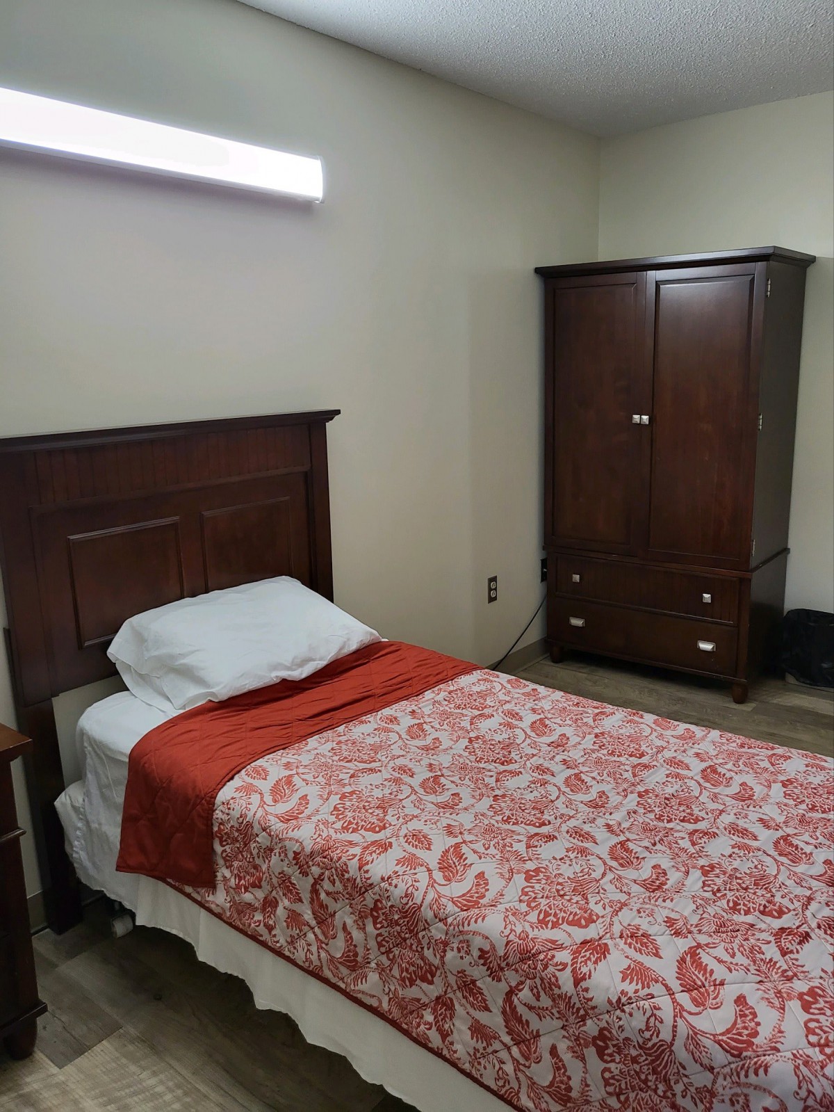 A cozy bedroom features a single bed with a patterned bedspread and a wooden wardrobe.