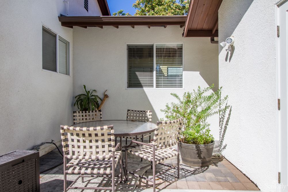 A cozy outdoor patio with a round table and four chairs, surrounded by potted plants.