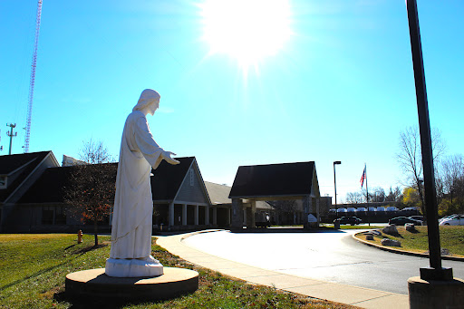 A serene statue in front of a building, basking in sunlight.