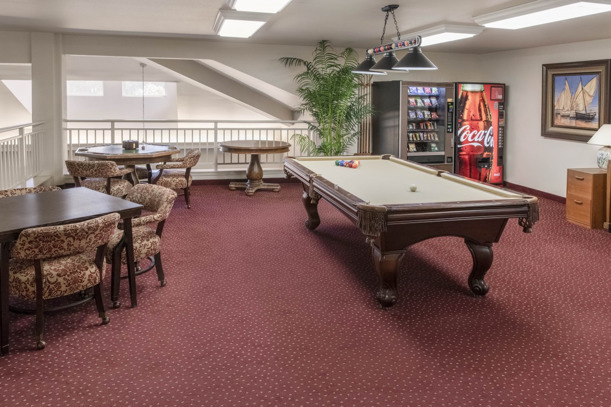 A game room with a pool table, seating area, and a vending machine.