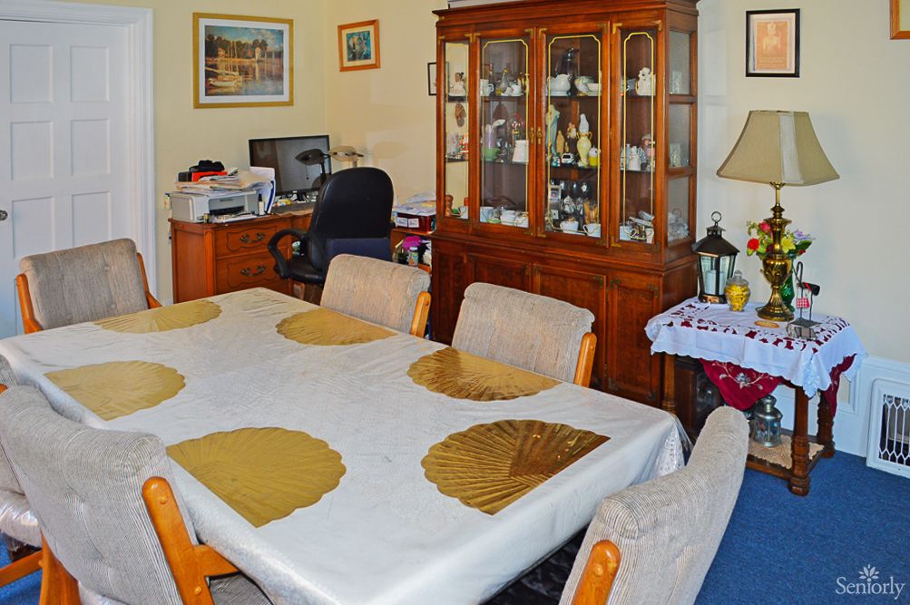 A cozy dining room with a table, chairs, and a wooden cabinet filled with decor.