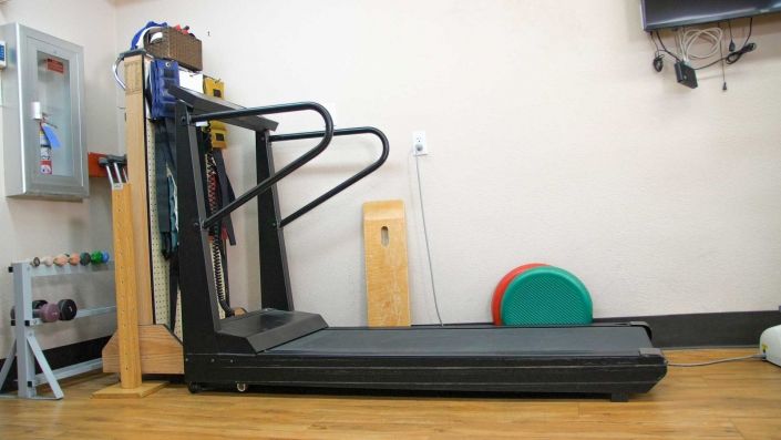 A treadmill in a gym setting with exercise mats nearby.