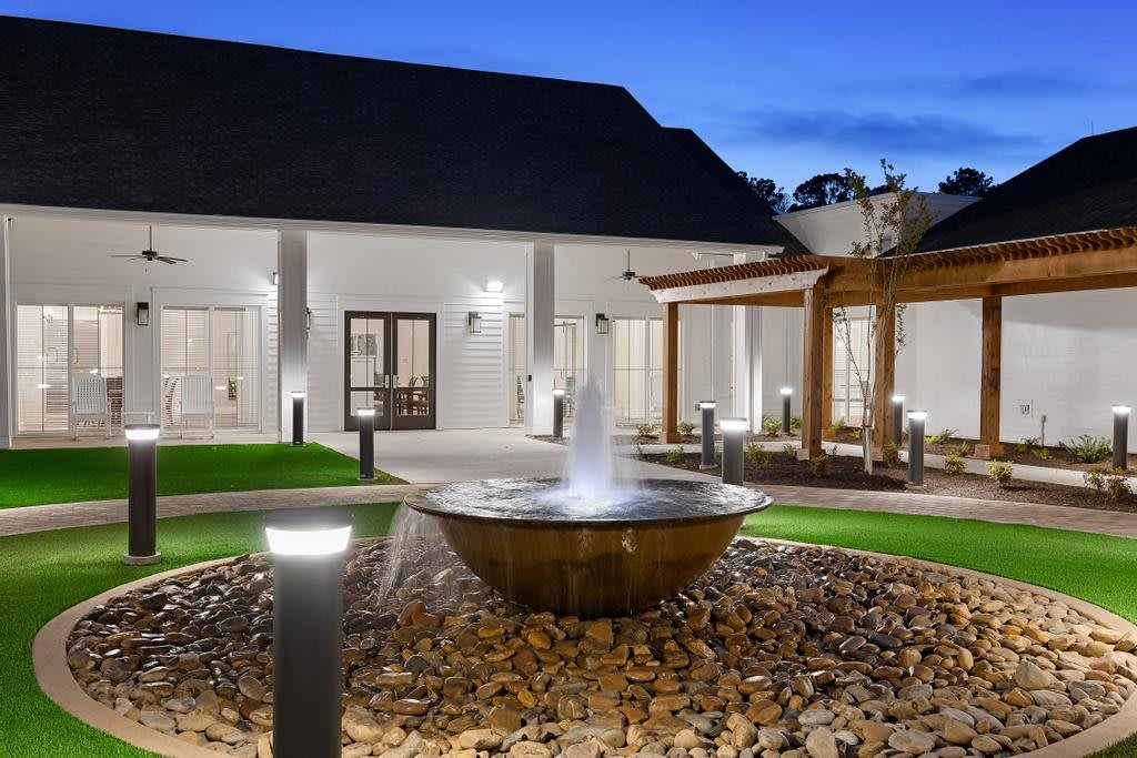A beautifully lit courtyard at night featuring a central fountain surrounded by modern architecture.