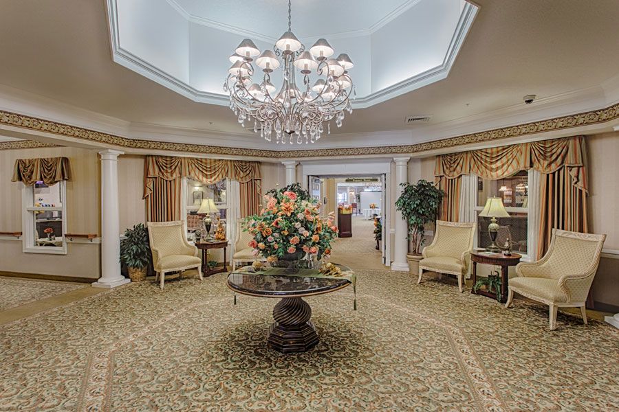 A luxurious lobby featuring a grand chandelier, elegant furniture, and a central floral arrangement.