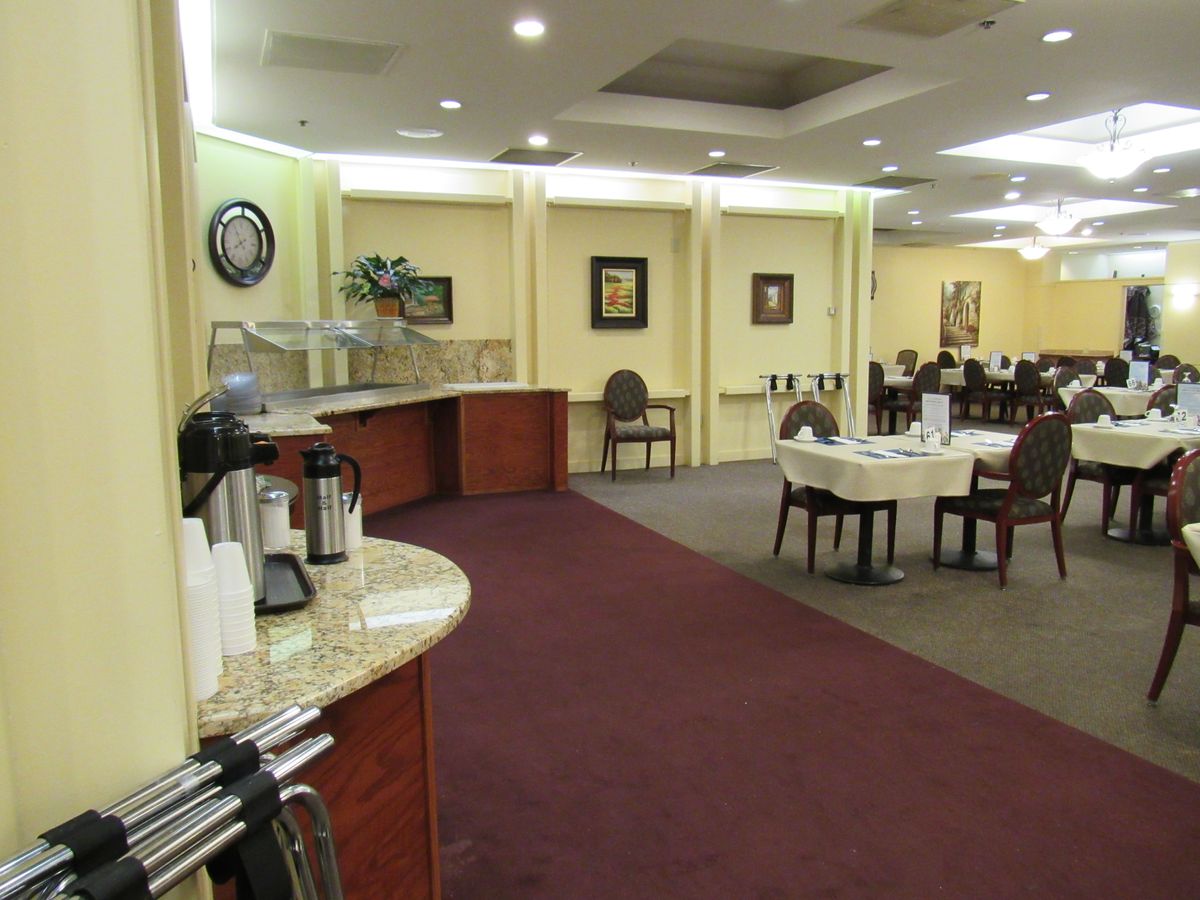 An elegantly arranged dining area with neatly set tables and chairs, featuring warm lighting and tasteful decor.