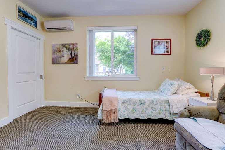 A cozy bedroom with a single bed, window, and wall decorations.