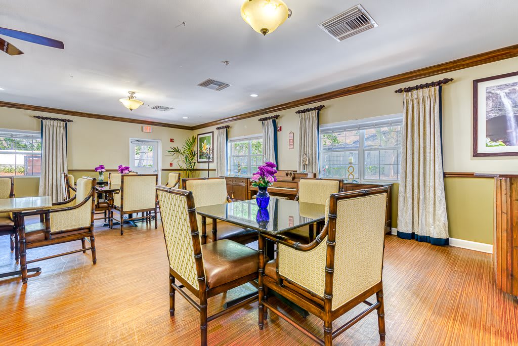 A well-lit dining area featuring elegant tables and chairs, adorned with floral centerpieces.