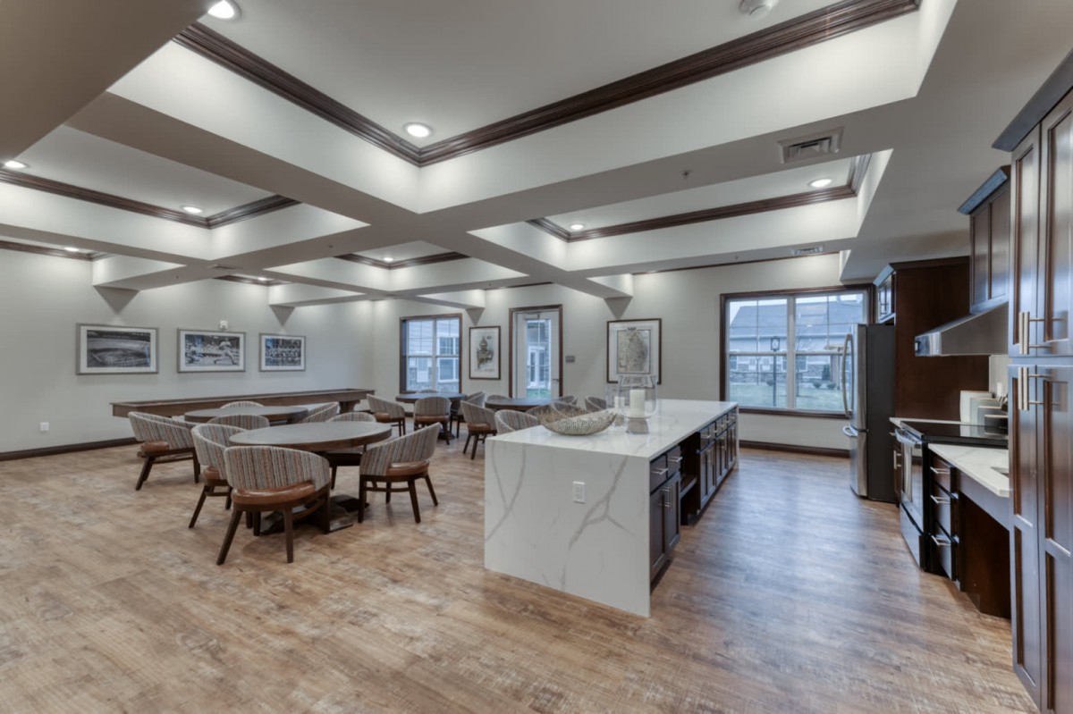 A modern open-concept dining and kitchen area with a sleek marble island and wooden flooring.
