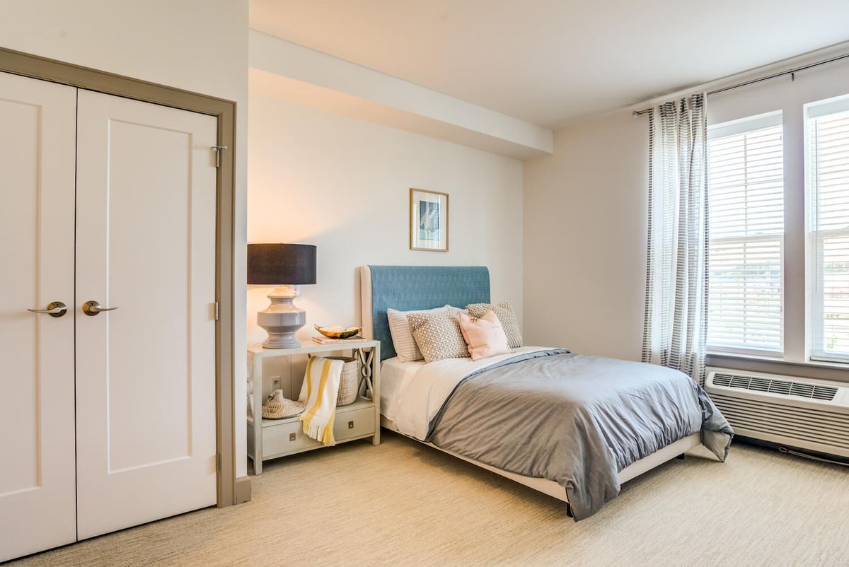 A modern and cozy bedroom with a blue headboard, soft bedding, and a stylish nightstand.