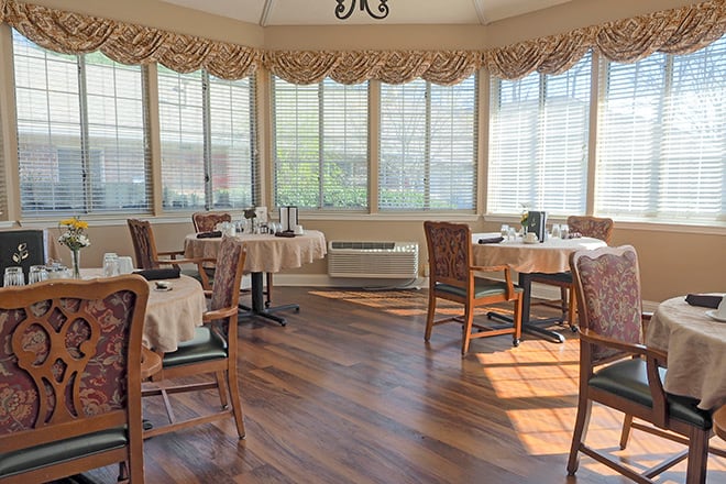 Sunlit dining room with neatly arranged tables and chairs.