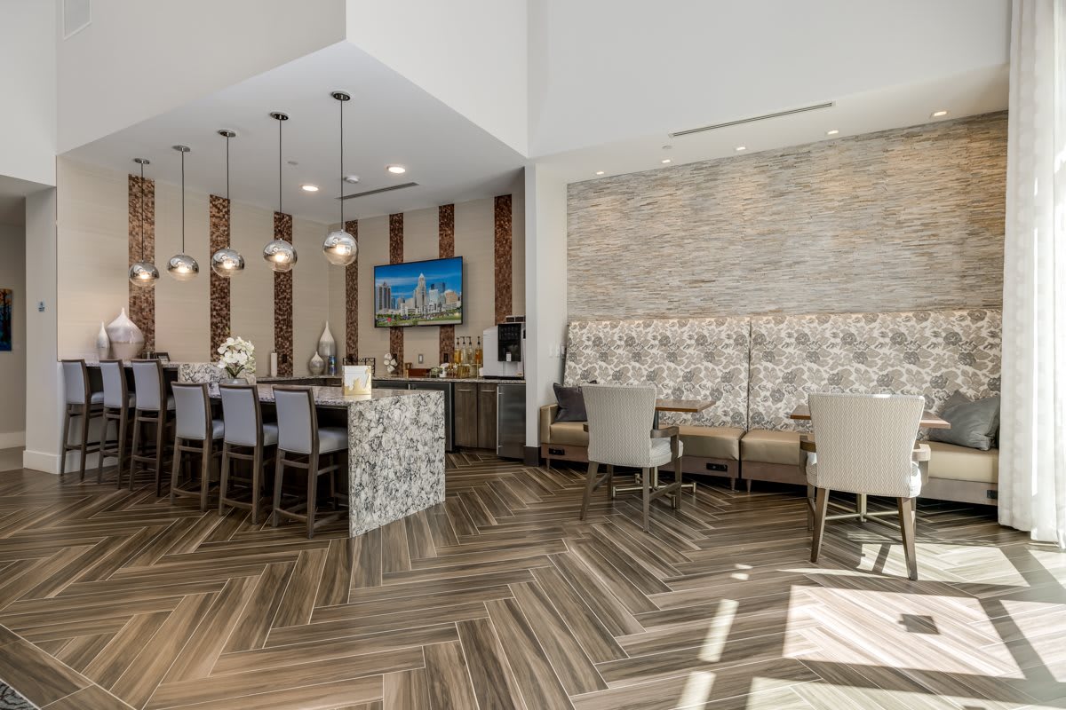 A modern lounge area featuring a bar counter with pendant lights and herringbone flooring.