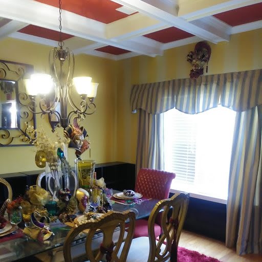 A colorful dining room with a decorated table and an elaborate chandelier, featuring mirrors and a creatively designed ceiling.