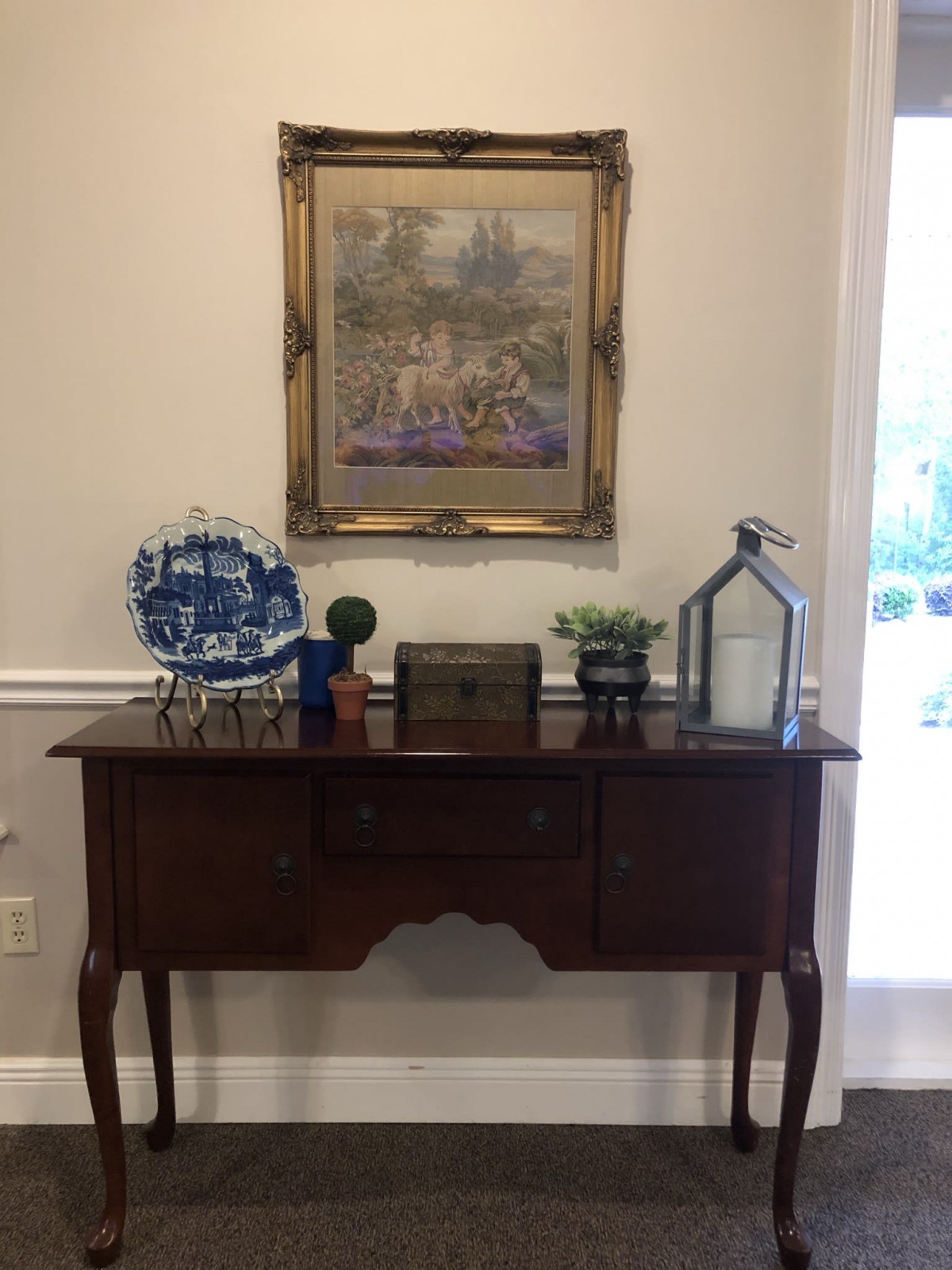 A vintage wooden table with decorative items and a framed painting above it.