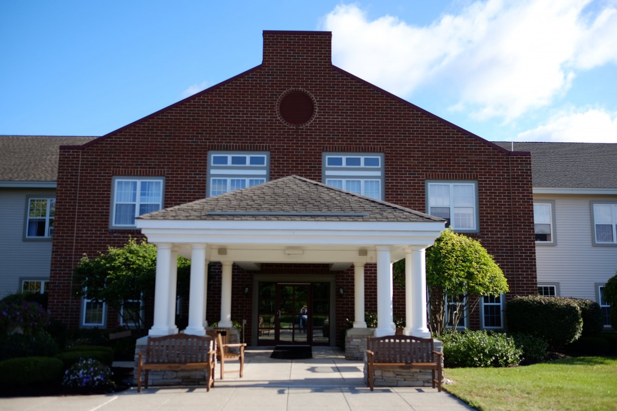 A brick building with a columned entrance and a porch area.
