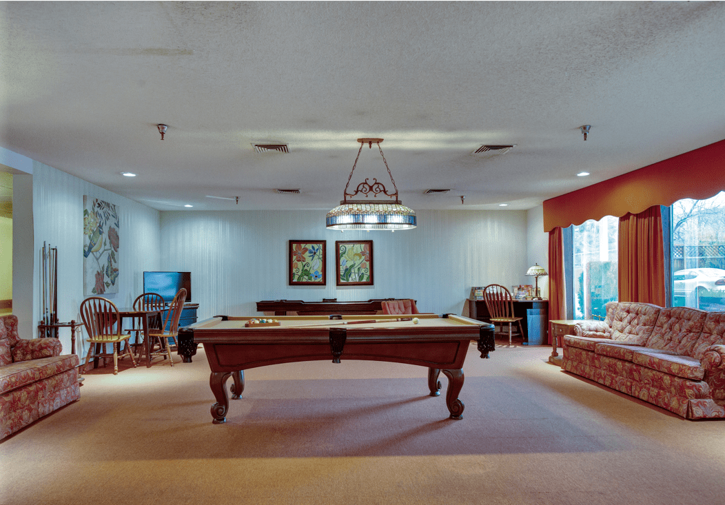 A spacious billiards room featuring a pool table under elegant lighting.