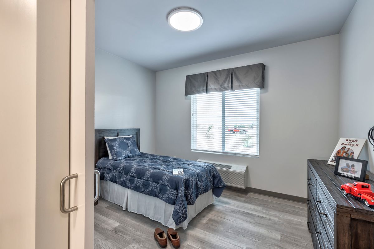 A modern bedroom with a single bed and large window.