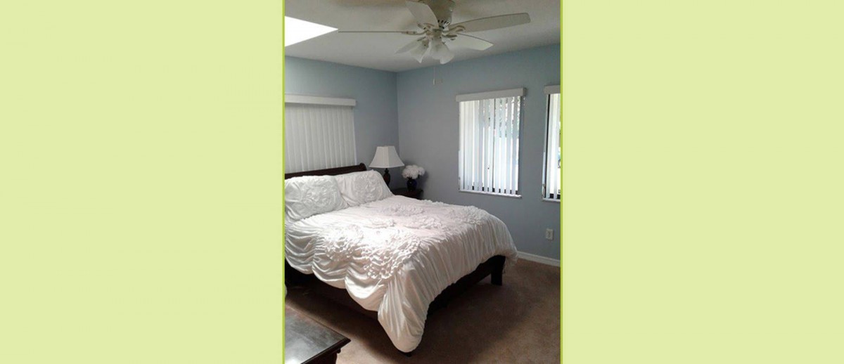 A cozy bedroom with a comfortable bed, two windows, and a ceiling fan.