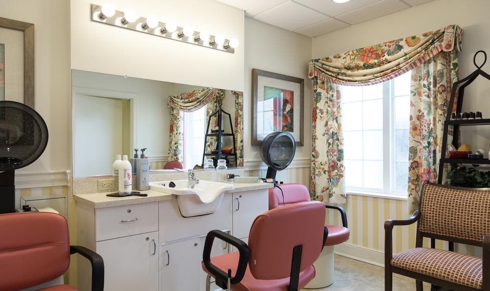 A cozy hair salon with pink chairs and floral curtains.