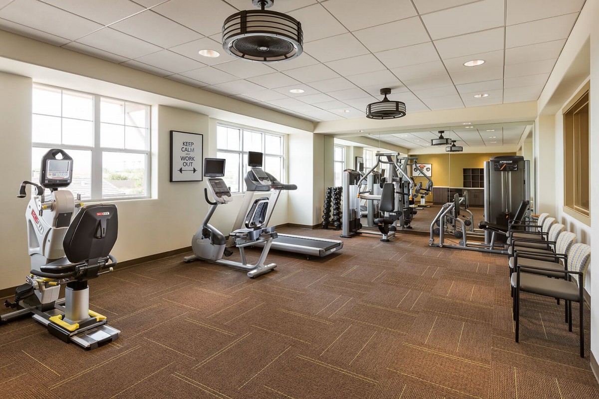 A modern gym with various exercise equipment including treadmills and elliptical machines.