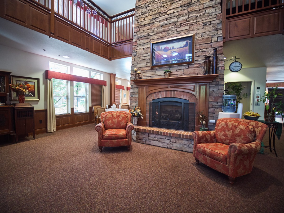 A cozy living room with a stone fireplace and two comfortable armchairs.