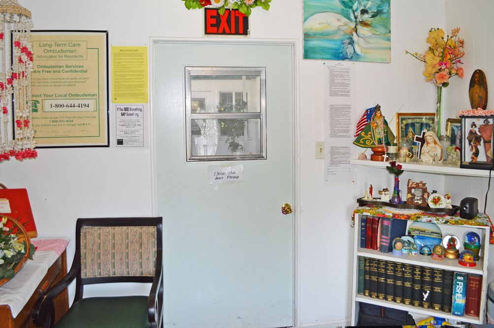 An interior view of an office space with a central door marked by an exit sign, surrounded by various decorations and a bookshelf.