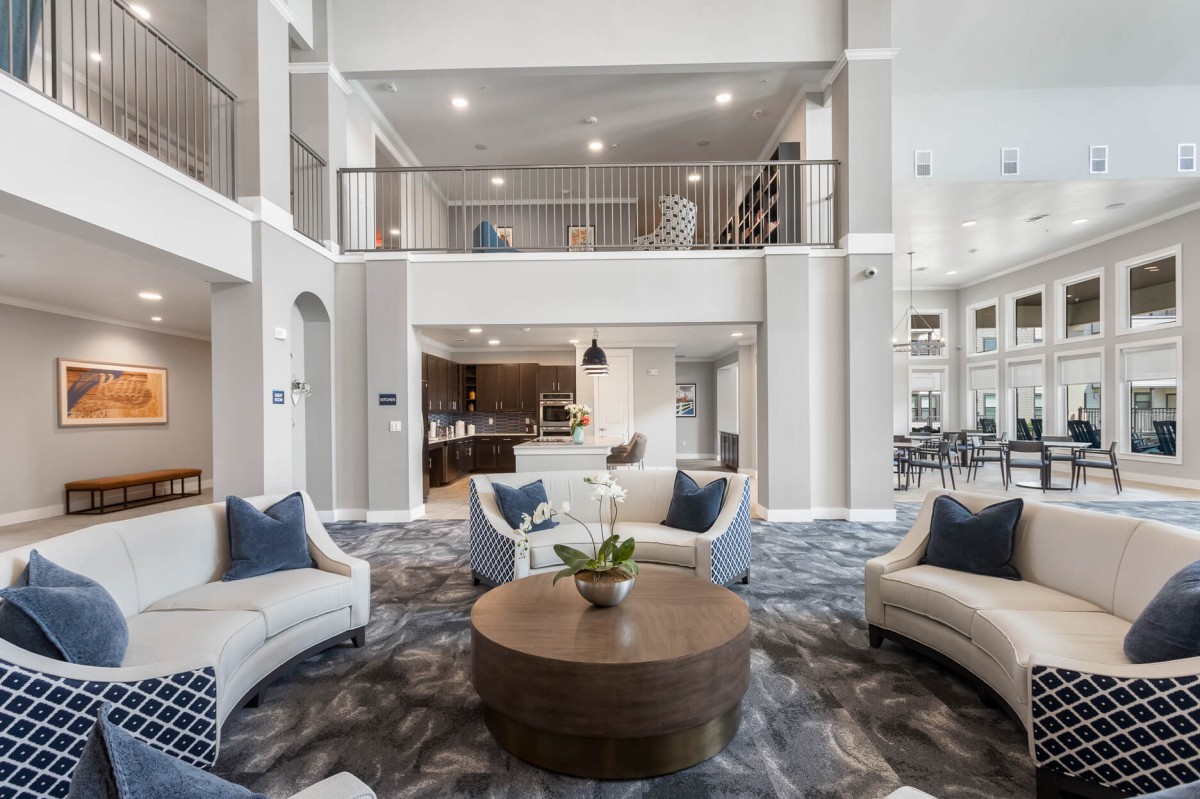A spacious and elegantly designed living room with a contemporary open floor plan, featuring modern furniture and abundant natural light.