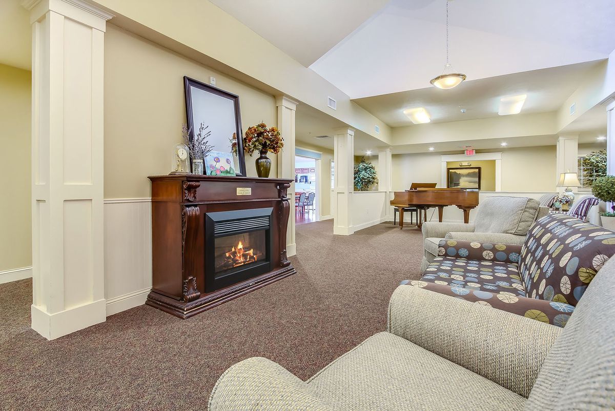 A cozy living room featuring a fireplace, grand piano, and comfortable seating.