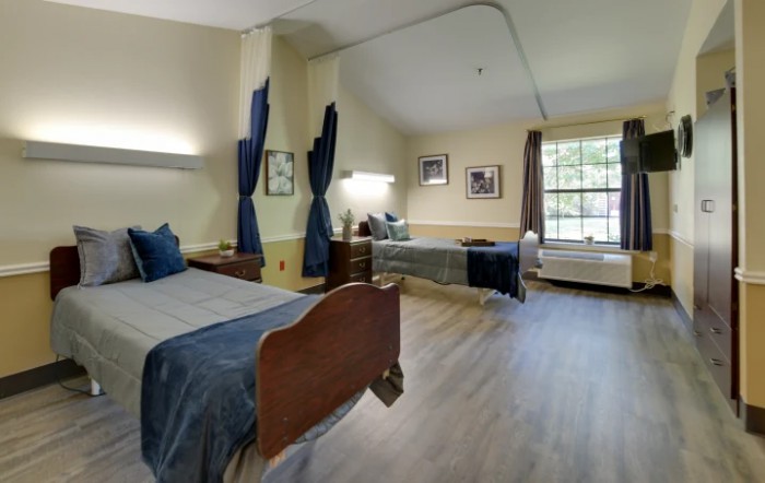 A cozy bedroom with two beds, elegant furnishings, and natural light from a large window.