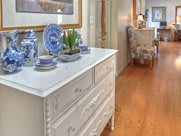 A cozy hallway with a vintage white dresser adorned with blue and white porcelain decor, set against a warm hardwood floor.