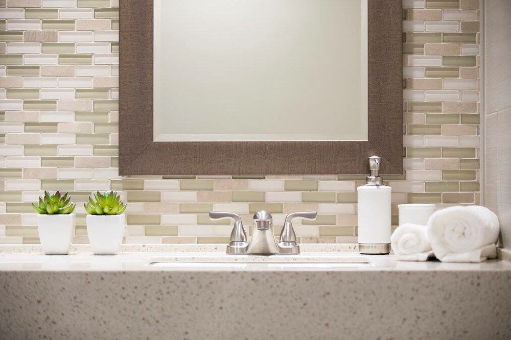 A modern bathroom vanity with a mirror, sink, and soap dispenser.