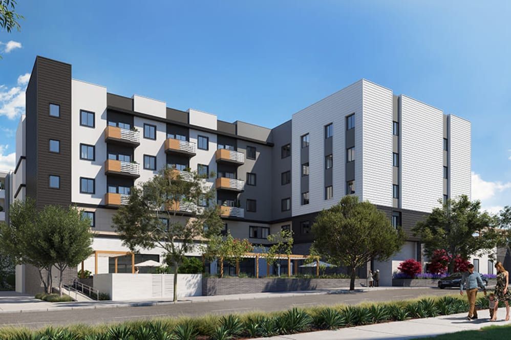 A modern apartment building featuring multiple balconies and surrounded by trees.