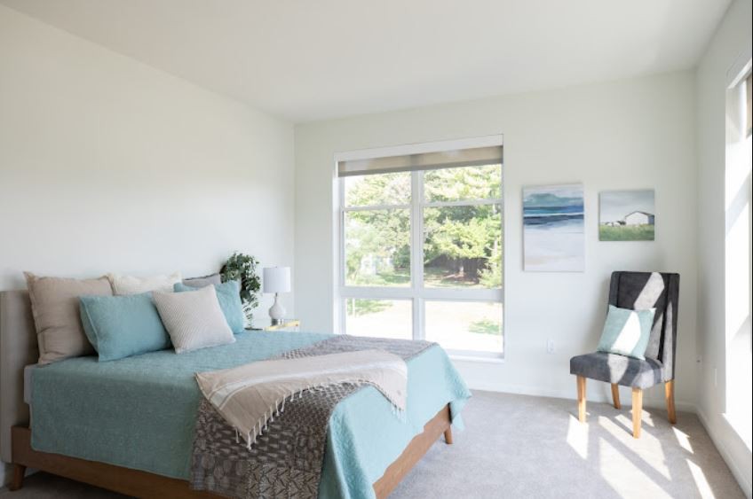A bright and modern bedroom with minimalist decor, featuring a comfortable bed and large window.