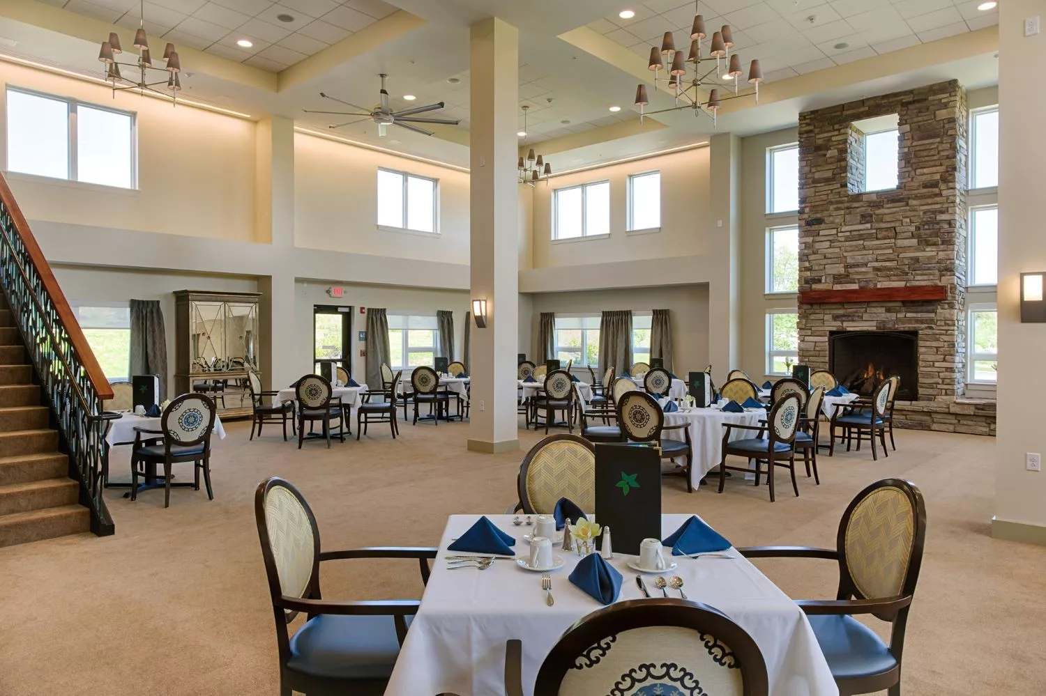 An elegant dining room with neatly arranged tables and chairs, featuring modern decor and ample natural lighting.