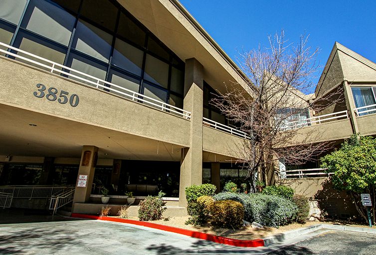A modern office building with large windows and a landscaped entrance.