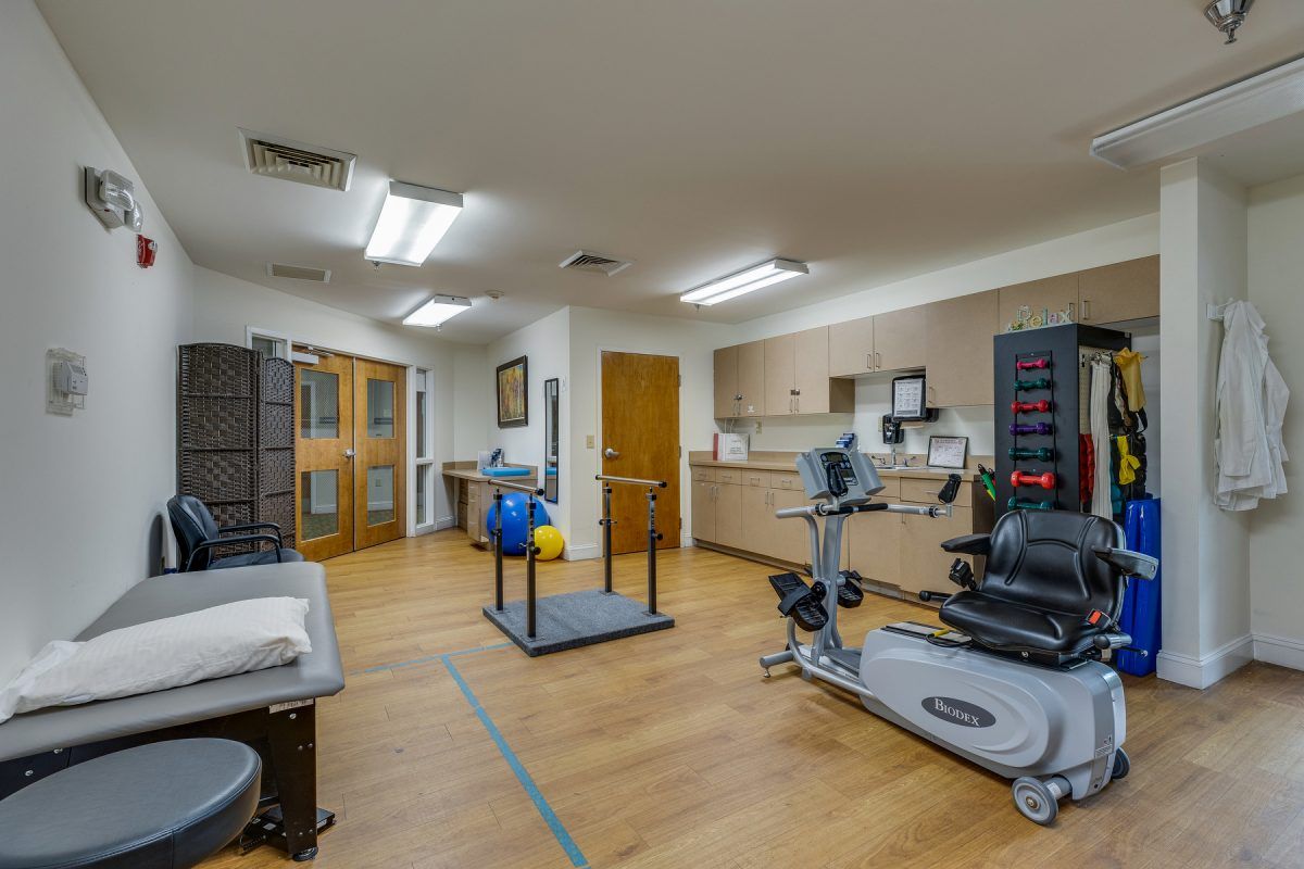 A well-equipped rehabilitation and physical therapy room with various exercise machines and equipment.