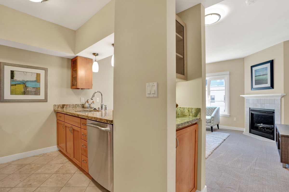 A modern kitchen with wooden cabinets and stainless steel appliances in an open-layout apartment.
