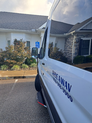 A view of a van parked in a lot, showcasing a handicapped parking sign and the surrounding landscaping.