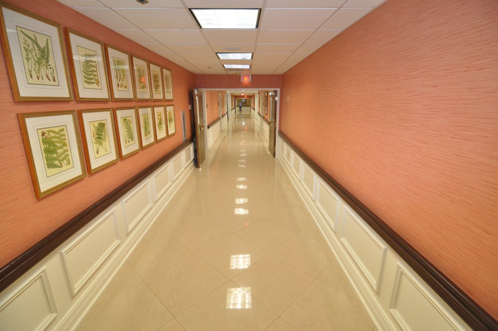 A long, well-lit hallway with framed art on the walls and clean tile flooring.