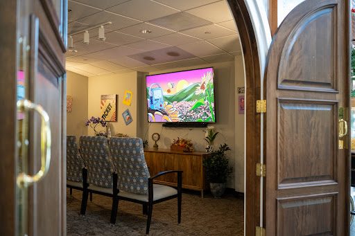 A cozy waiting room with comfortable seating and a vibrant television display.