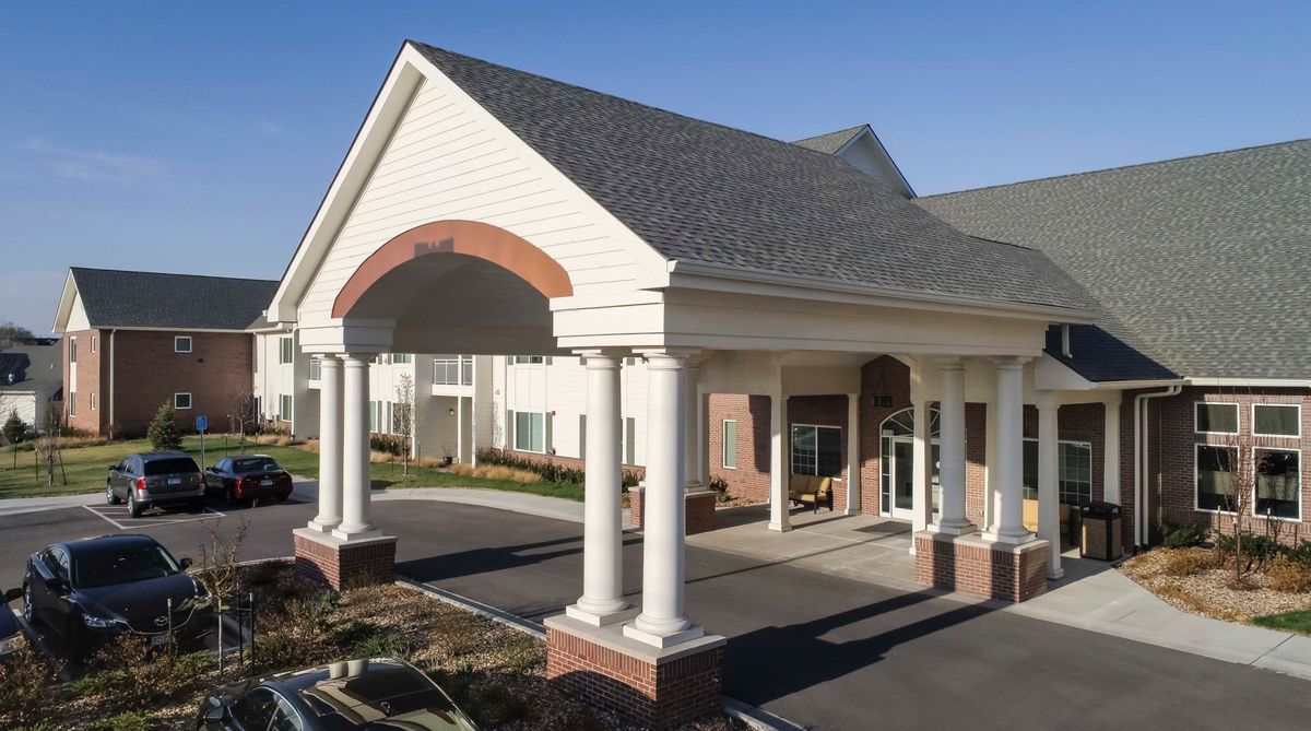 A building entrance featuring classical columns and a peaked roof.