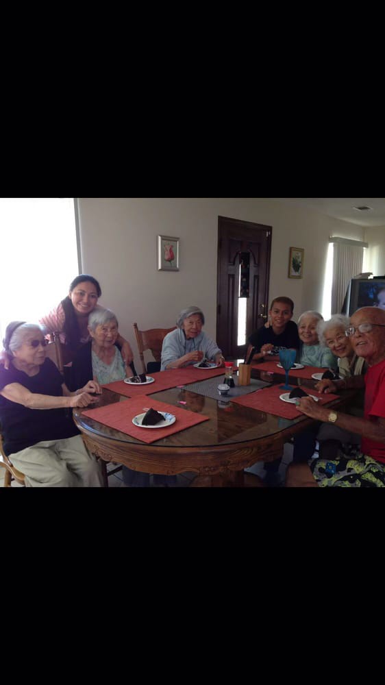 A group of people, mostly seniors, gathered around a table indoors.