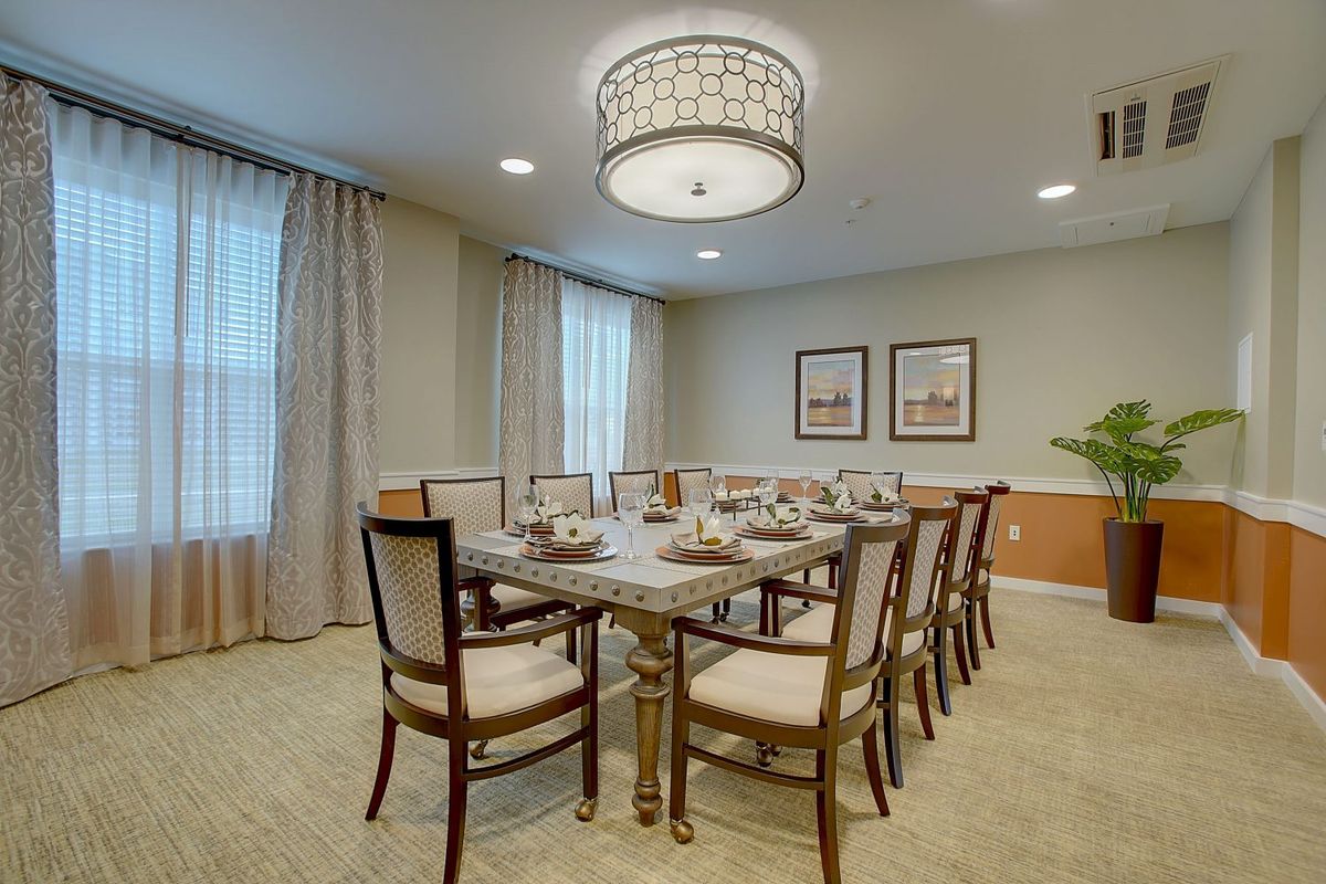 An elegant dining room with a large table, ornate chandelier, and sophisticated decor.