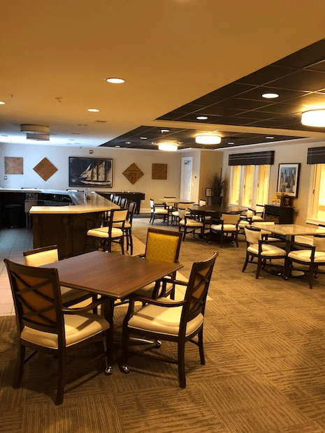 An empty dining area with neatly arranged tables and chairs, featuring warm lighting.