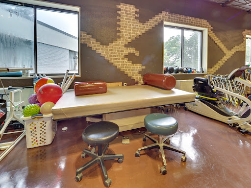 A well-equipped physical therapy room featuring a therapy table, exercise balls, and sleek seating arrangements.
