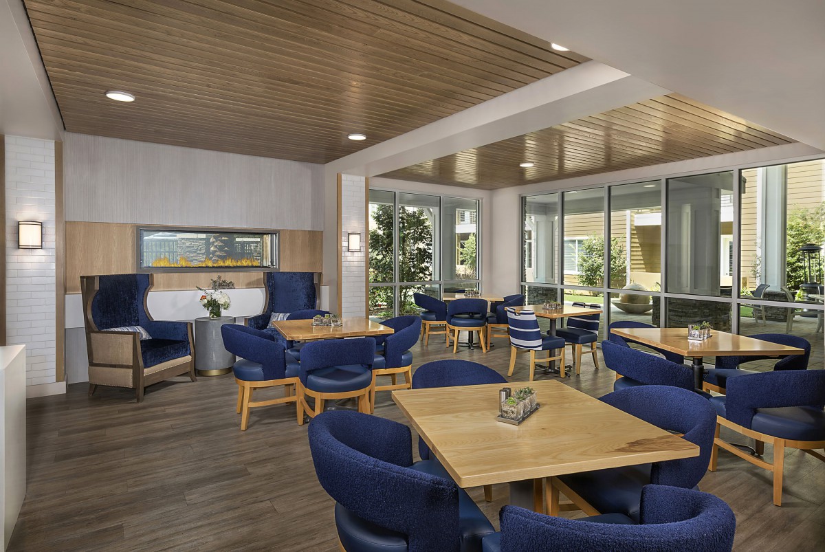 A modern dining area featuring blue chairs and wooden tables, with ample natural light.