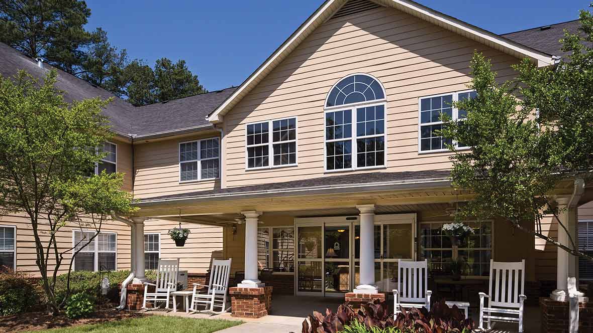 A charming two-story residential building with a welcoming porch and outdoor seating.