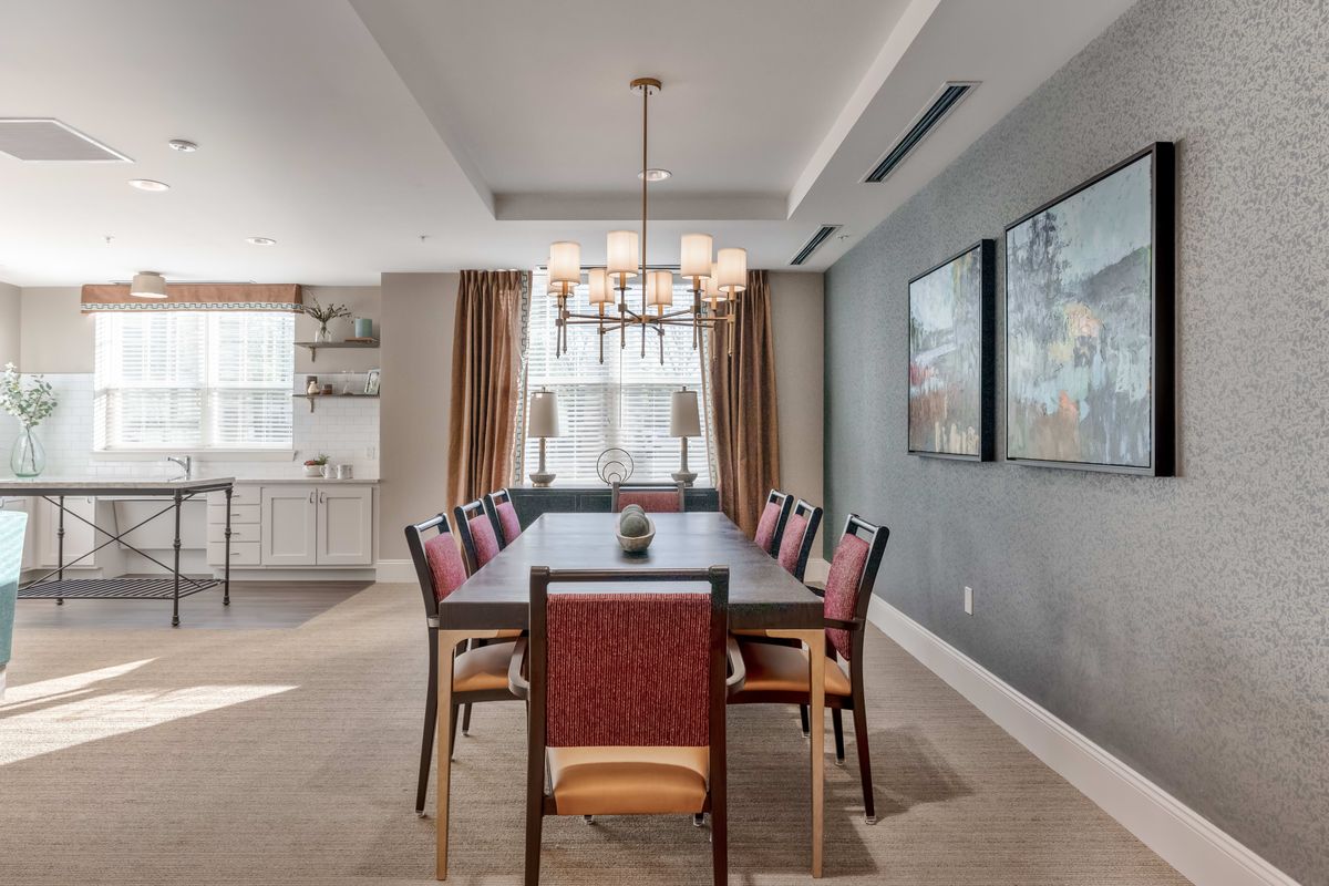 A modern dining room with a large table, elegant chairs, and a stylish chandelier.