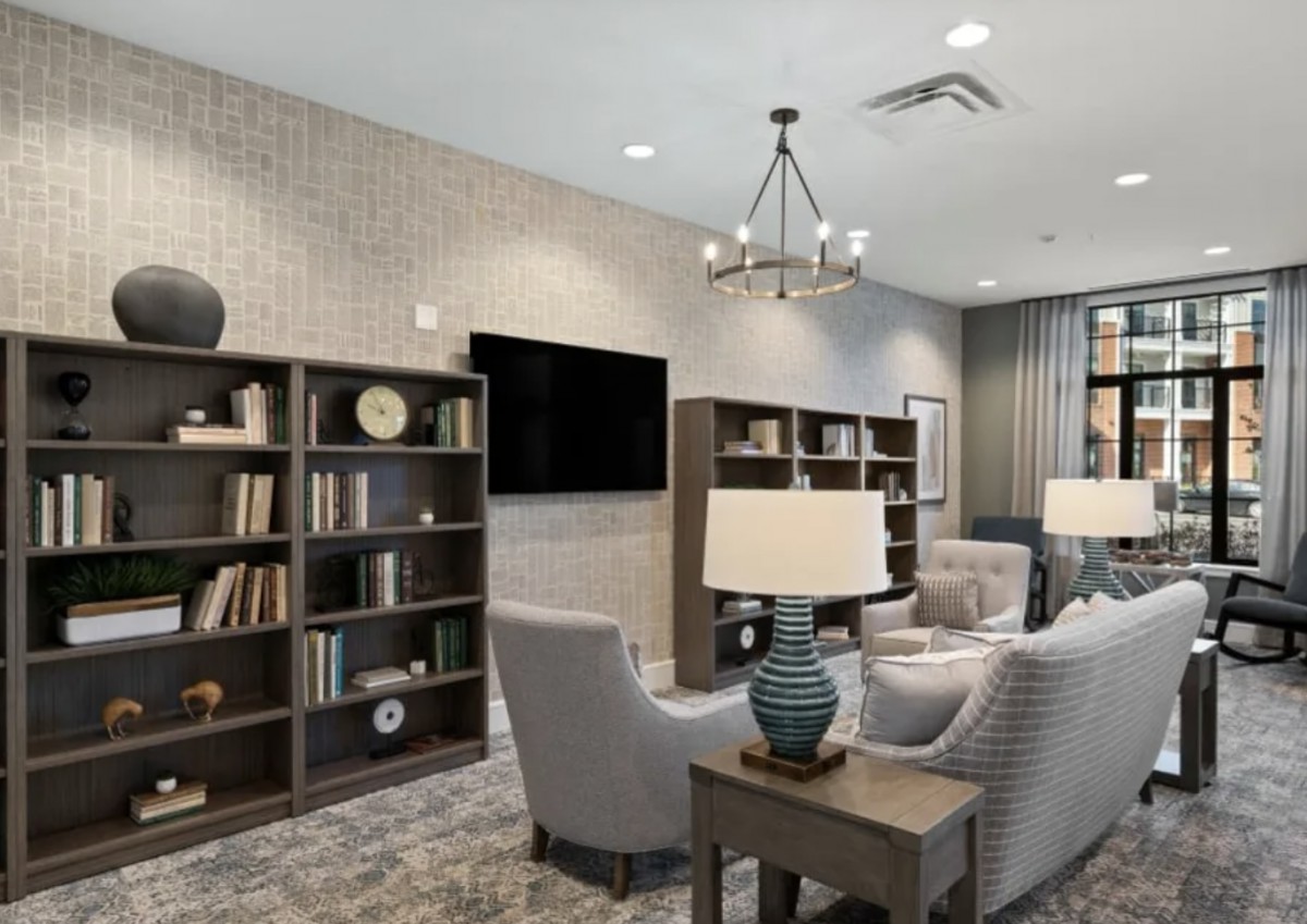 A cozy living room with bookshelves, comfortable seating, and a modern chandelier.