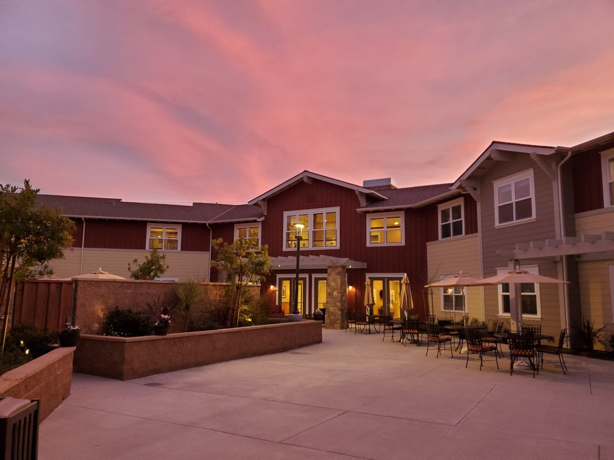 A beautiful building exterior at sunset with a cozy outdoor patio area.