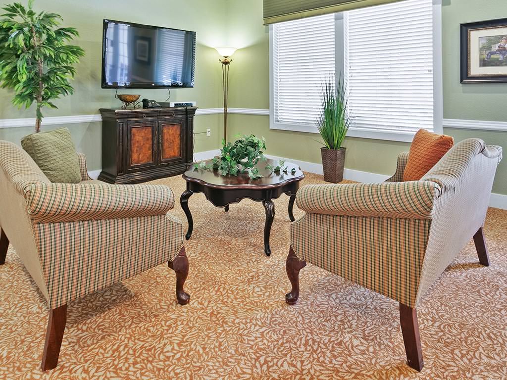 A cozy living room with striped chairs, a wooden coffee table, and a television mounted on the wall.